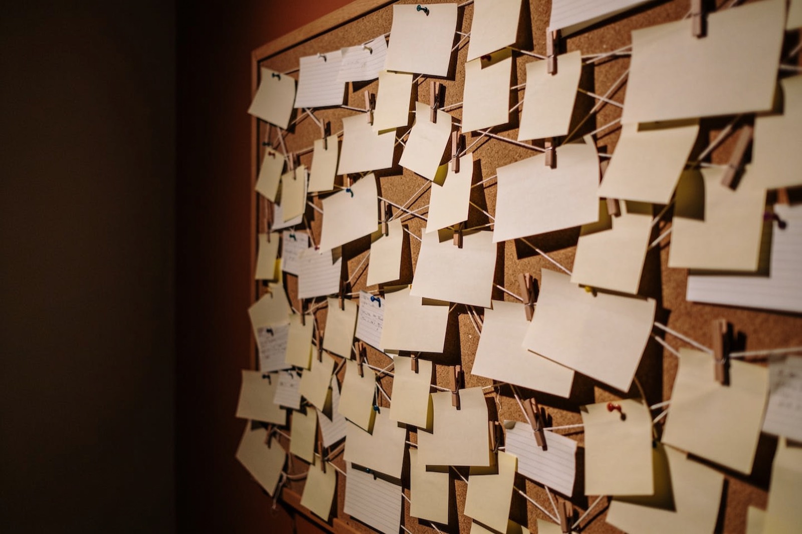 A corkboard crammed with scattered, pinned notes